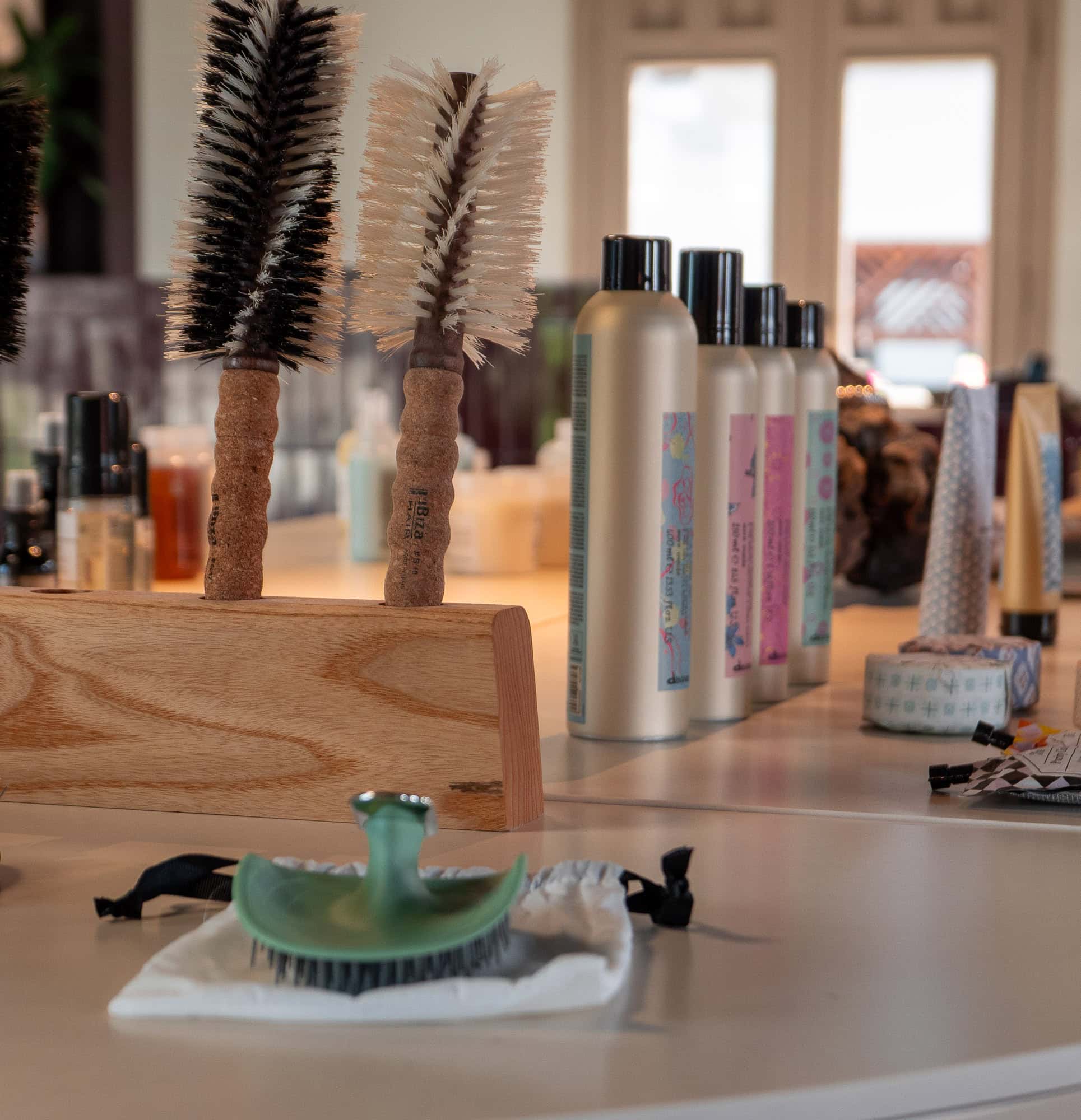 Close-up of hairbrushes, styling tools, and salon products arranged on a counter inside a Casco Viejo hair salon.