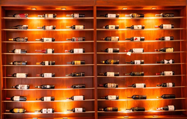Backlit wooden wine rack showcasing premium bottles at Afrodisíaco Italian Modern Kitchen in Casco Viejo