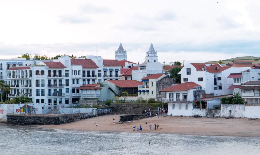 Beachfront view of Casco Viejo with historic colonial buildings and people enjoying the shoreline.