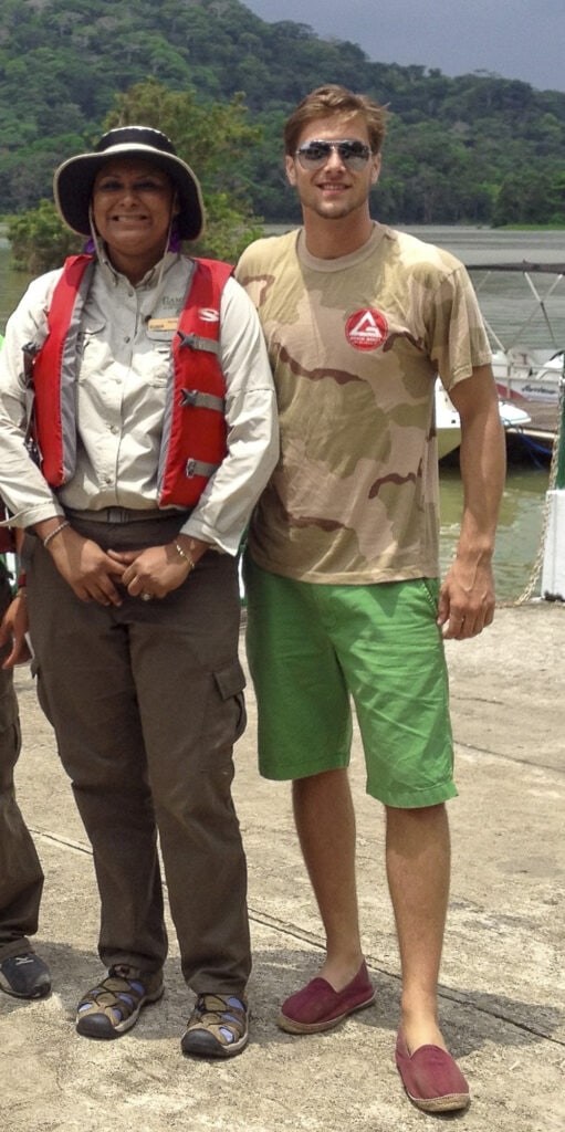 A Monkey Boat Tour guide and a tourist posing at the dock near Gamboa, with rainforest hills and boats in the background.