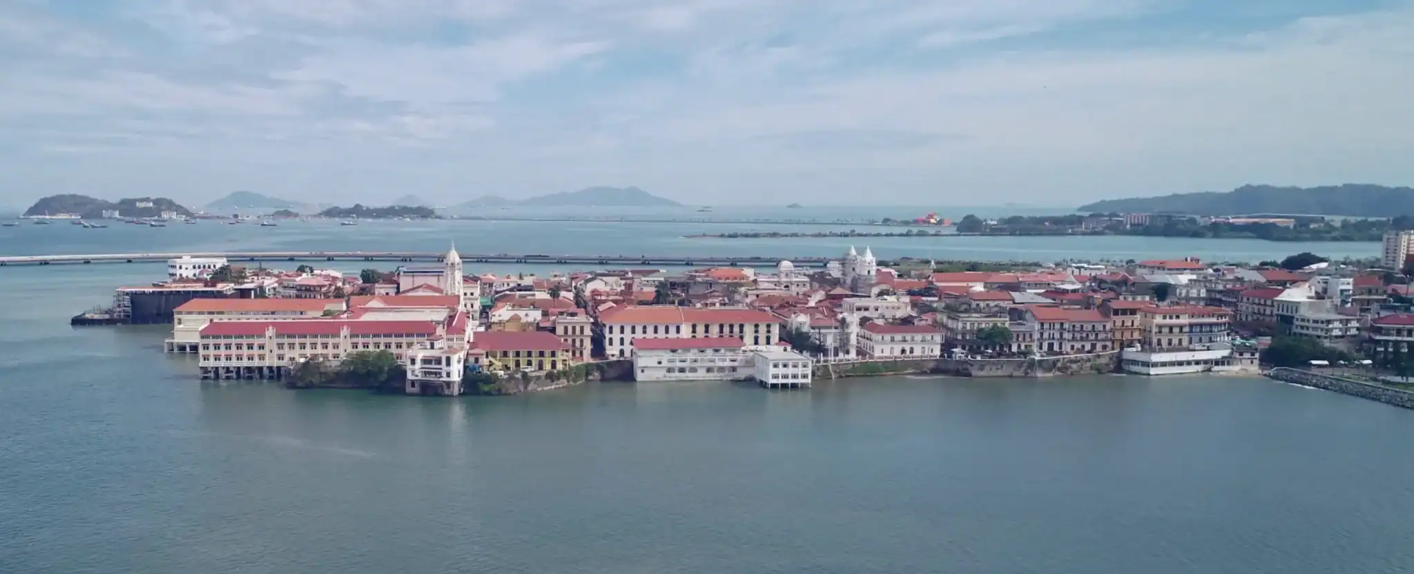 Panoramic aerial view of Casco Viejo, Panama, with red‑tile roofs and the Pacific beyond.