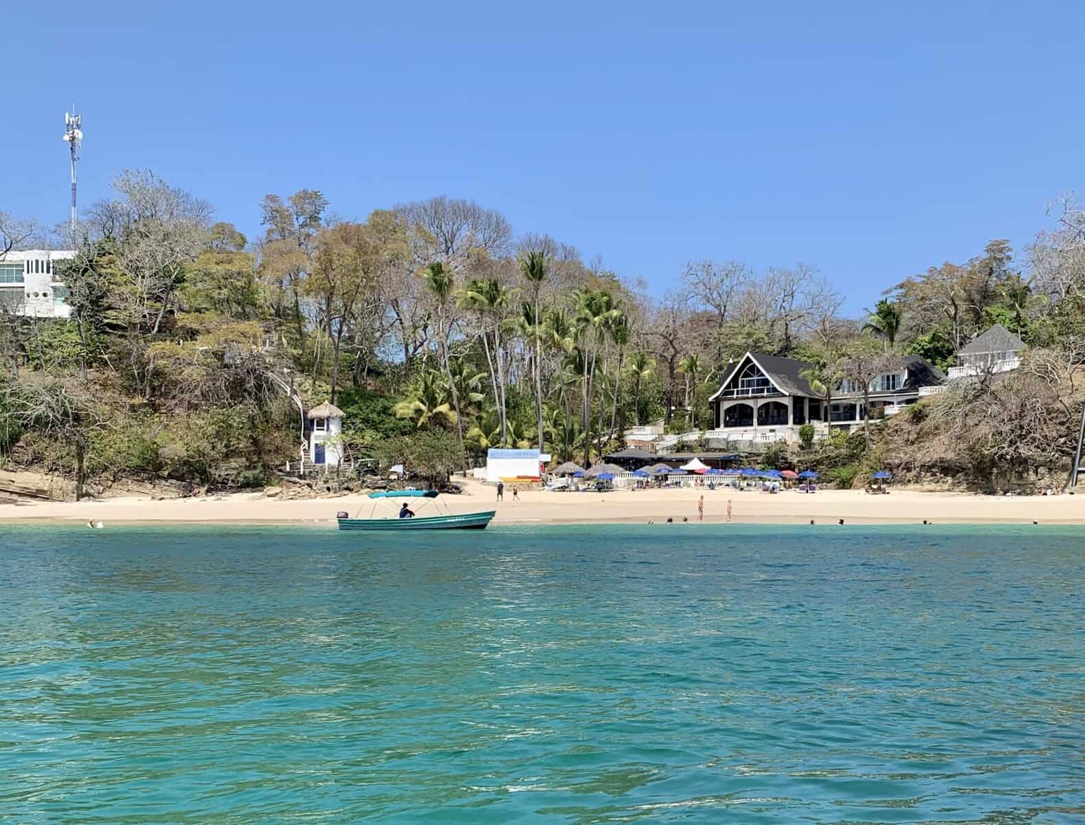 Beachfront view of Contadora Island, Panama, with turquoise waters and lush hillside homes.