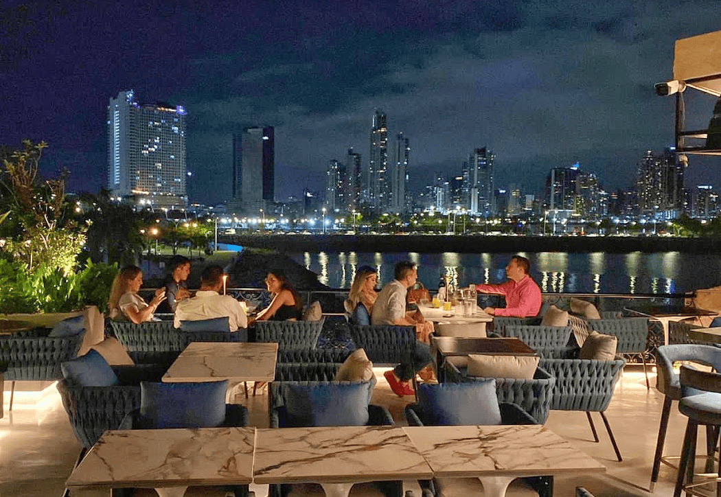 Guests enjoying cocktails at Mazatlán Rooftop in Casco Viejo with Panama City skyline at night