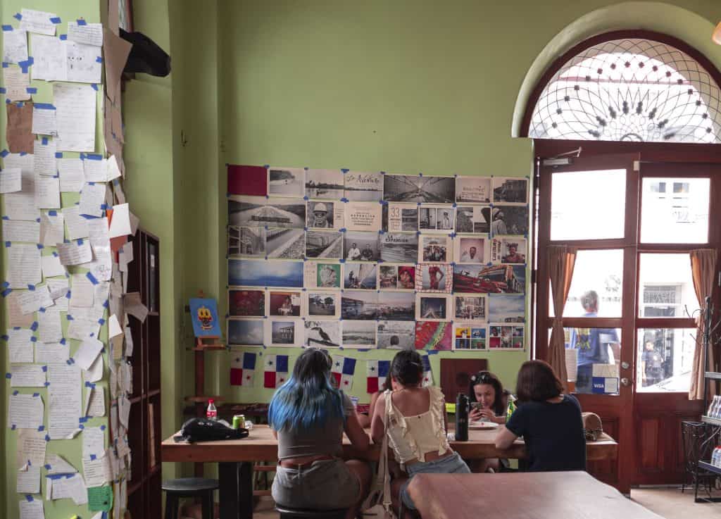 Guests seated at Super Gourmet café in Casco Viejo, near community wall filled with handwritten notes and photos