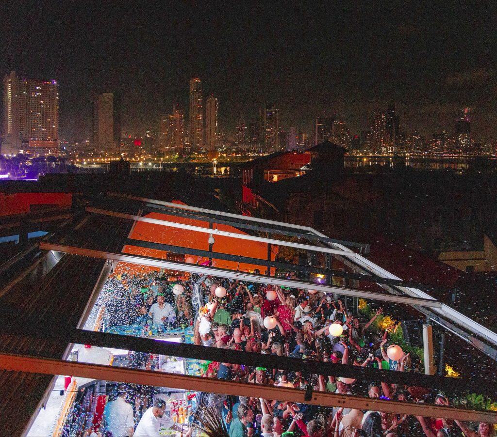 Crowd celebrating at Tantalo Rooftop Bar in Casco Viejo with Panama City skyline at night