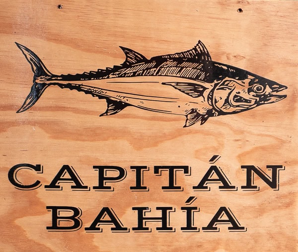 Authentic seafood sign for Capitán Bahía in Casco Viejo, Panama, featuring a fresh tuna illustration and rustic wood background.