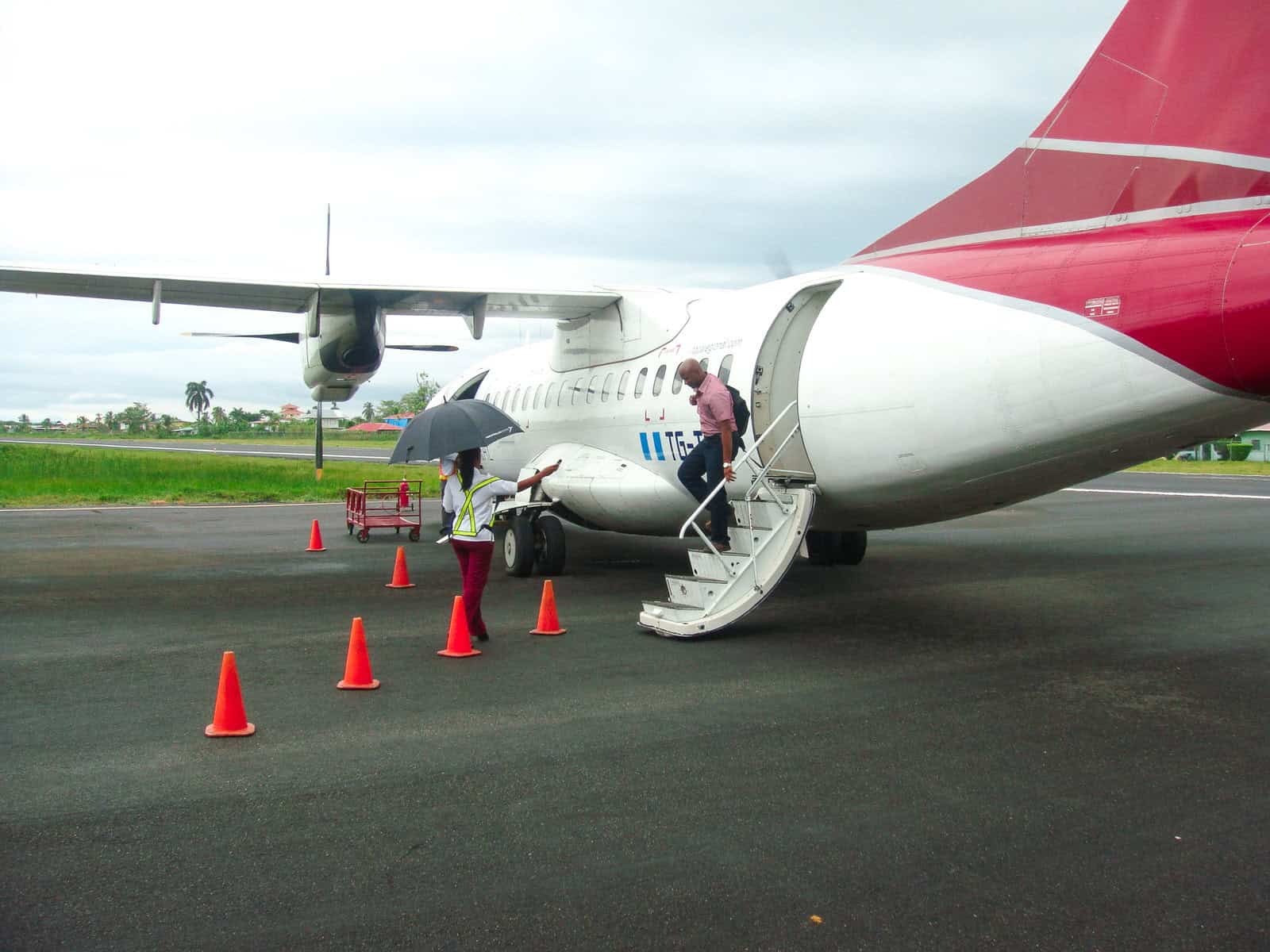 Passengers boarding a small Air Panama turboprop aircraft on the tarmac at a regional airport in Panama