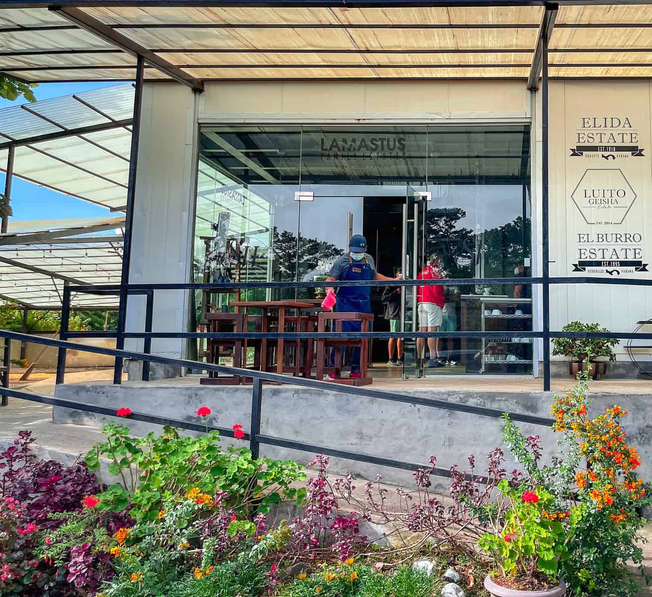 Visitors at the Elida Estate coffee tour welcome center in Panama with modern glass facade and landscaped garden