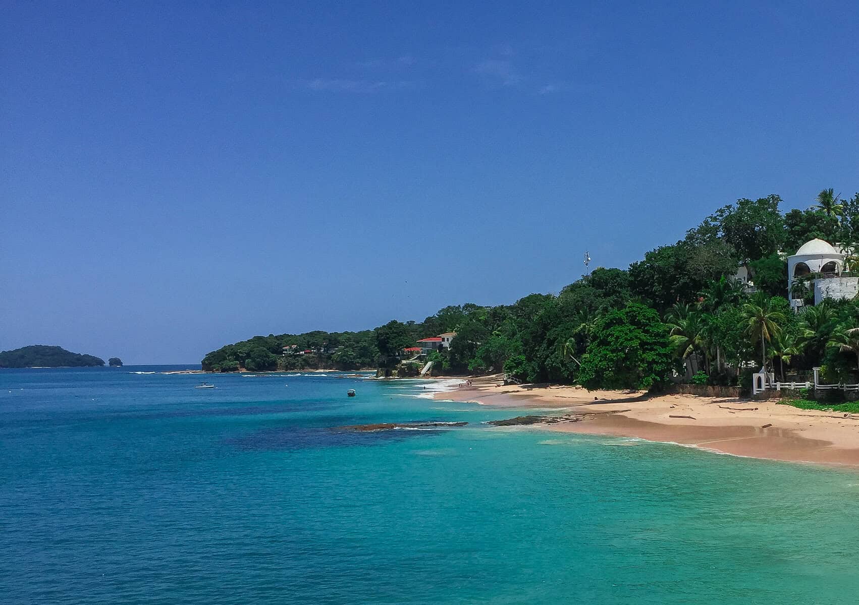 Turquoise waters and sandy beach on Contadora Island in the Pearl Islands of Panama with lush greenery along the shoreline