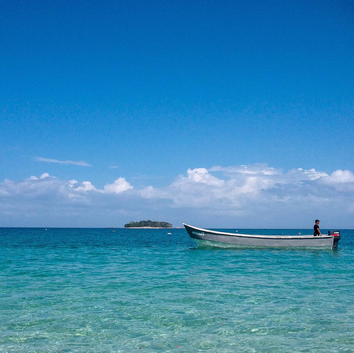 Small boat floating in clear turquoise water off Contadora Island in Panama’s Pearl Islands under a bright blue sky
