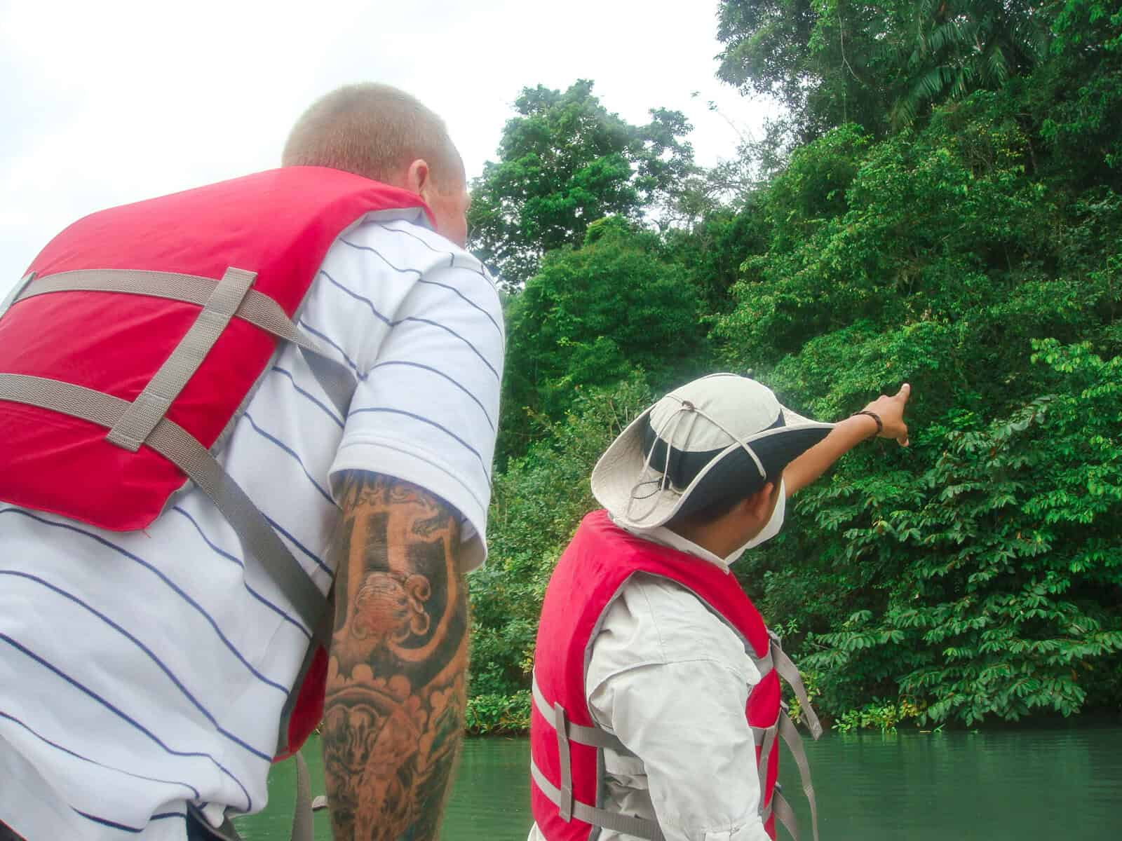 Guided river tour in Gamboa, Panama with visitors wearing life vests observing wildlife along the rainforest riverbank