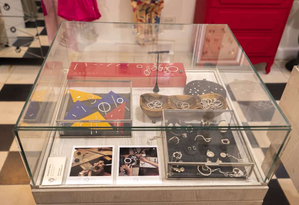 Glass jewelry display case at Arco Soleil in Casco Viejo, showcasing handmade earrings, rings, and postcards from local artists.
