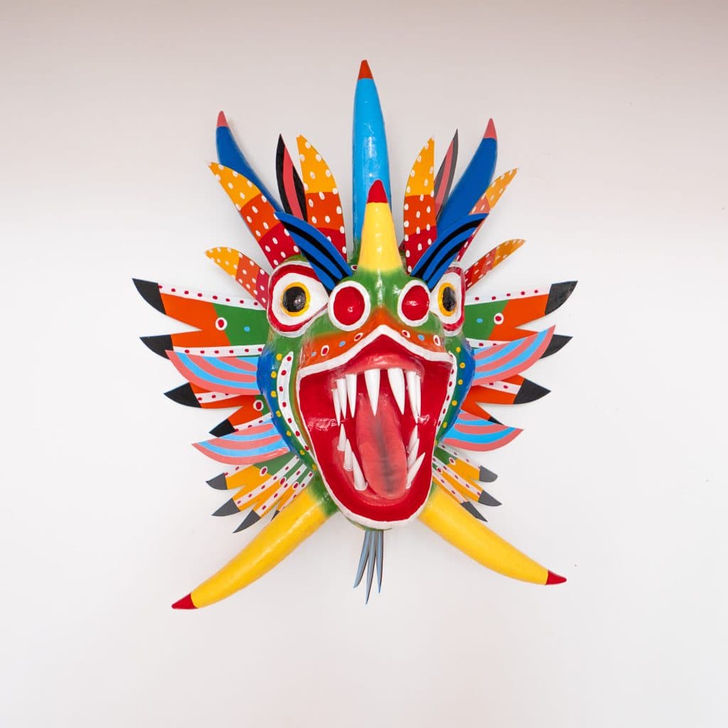 Colorful handcrafted Panamanian diablo mask with sharp teeth and feathers, displayed against a white background.