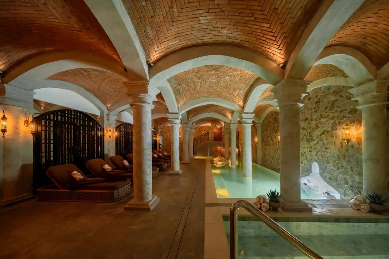 La Compañía Resort & Spa El Valle spa interior with vaulted brick ceilings, stone columns, thermal pools, and softly lit relaxation areas.