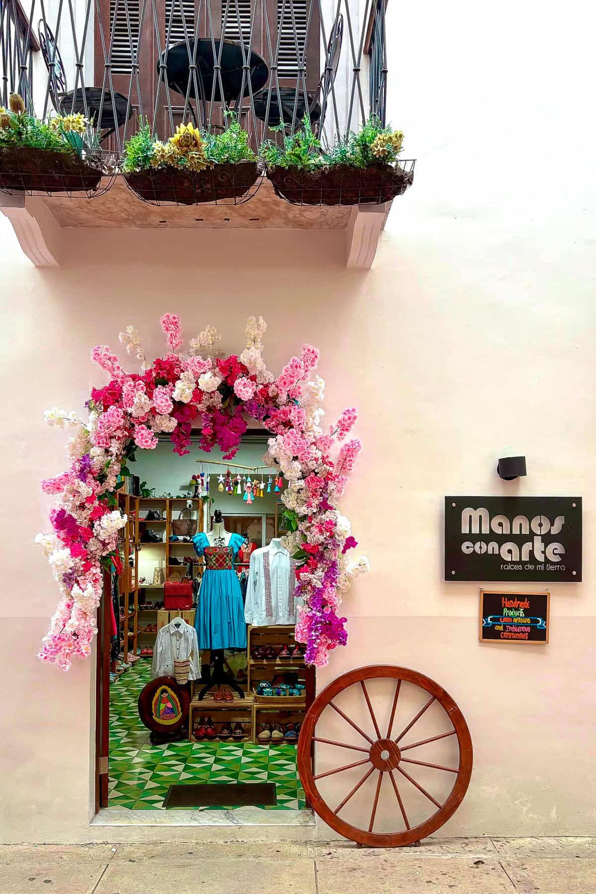 Entrance of Manos con Arte gift shop on Avenue A in Casco Viejo, Panama with floral archway and handcrafted clothing display