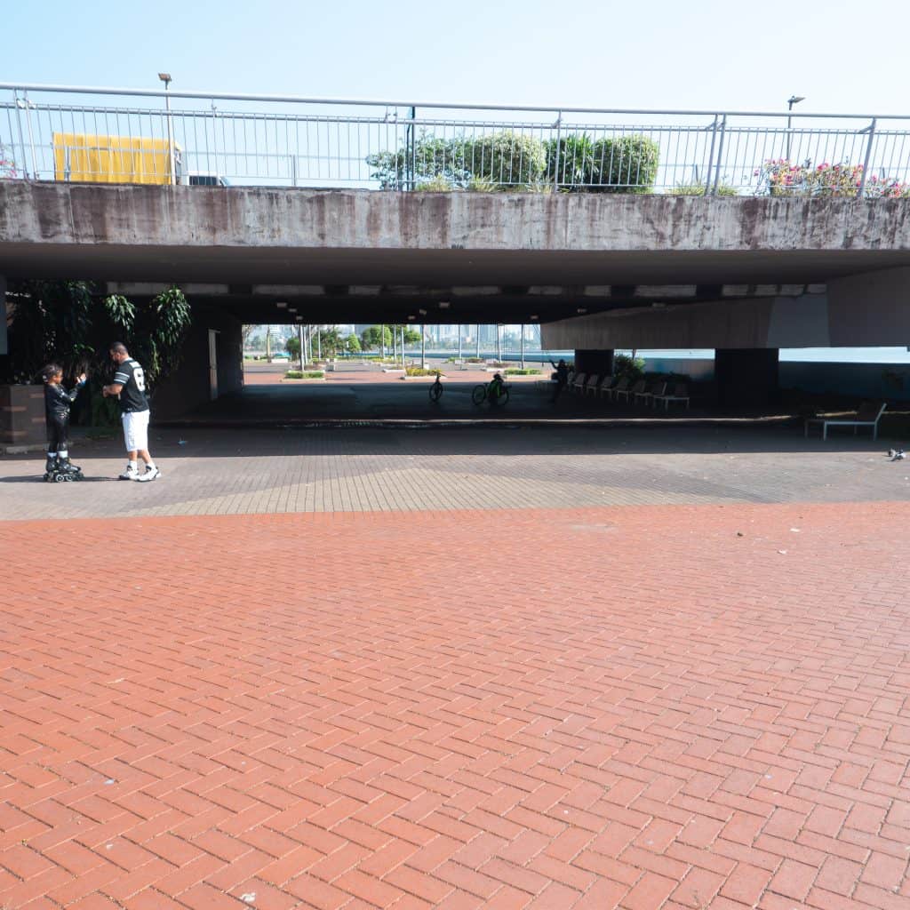 Pedestrian underpass connecting Casco Viejo to Cinta Costera 2 in Panama City with brick promenade, cyclists, and shaded waterfront walkway.