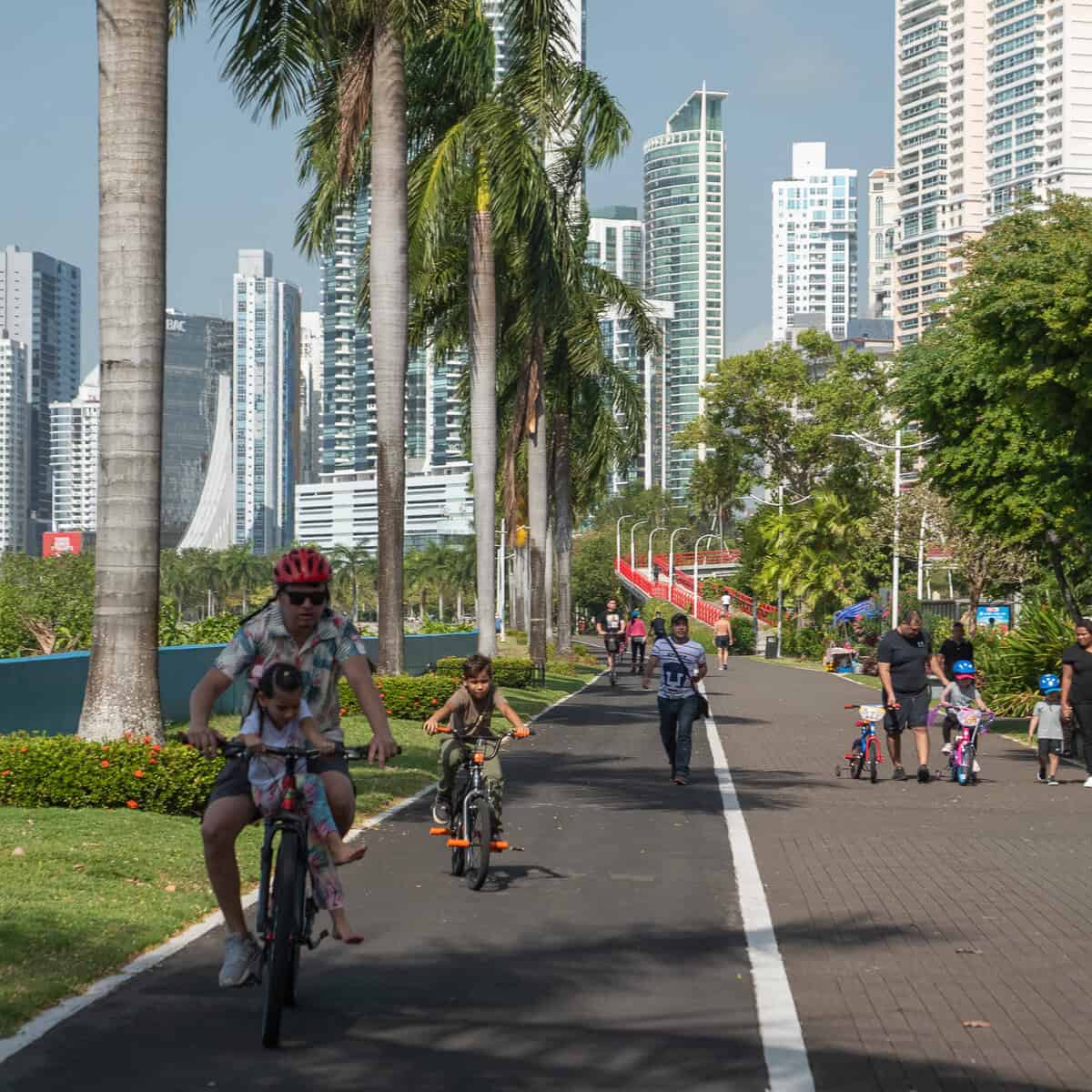 Families cycling along Cinta Costera 2 waterfront path in Panama City with high-rise skyline behind.