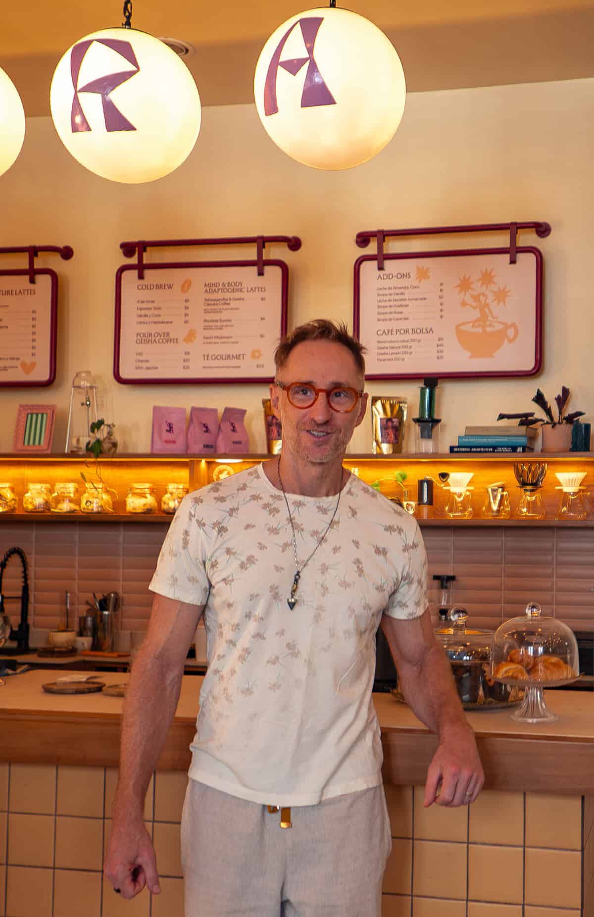 Matthew at Tantalo Hotel café in Casco Viejo Panama standing in front of counter with coffee menu and warm lighting