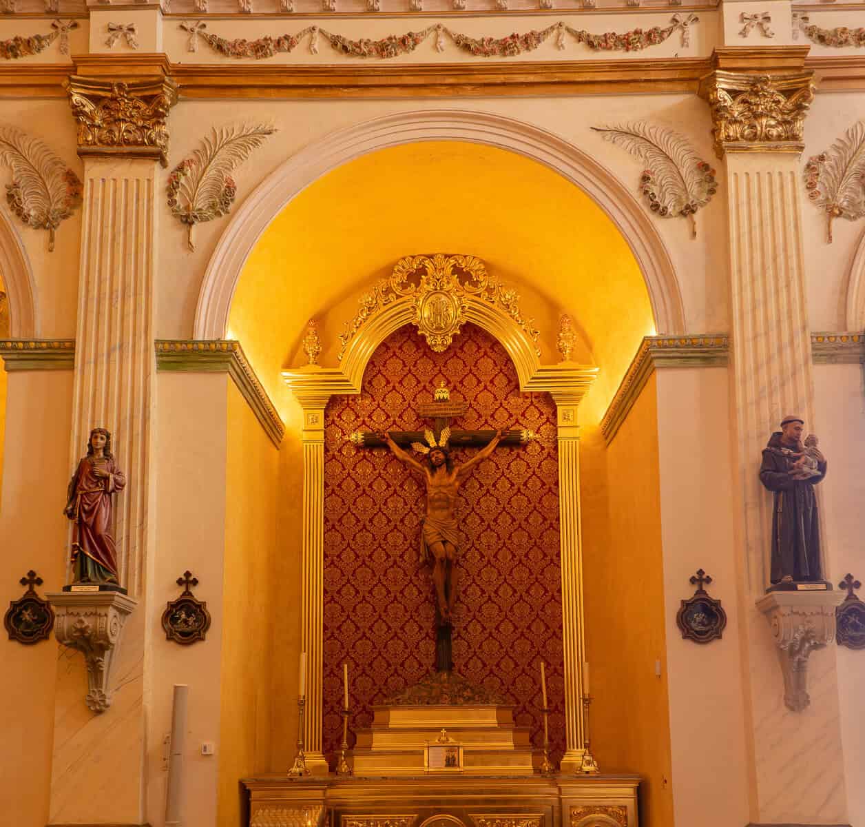 Crucifix and side altar inside the Oratorio San Felipe Neri in Casco Viejo, Panama City, framed by elegant colonial architecture and religious statues.