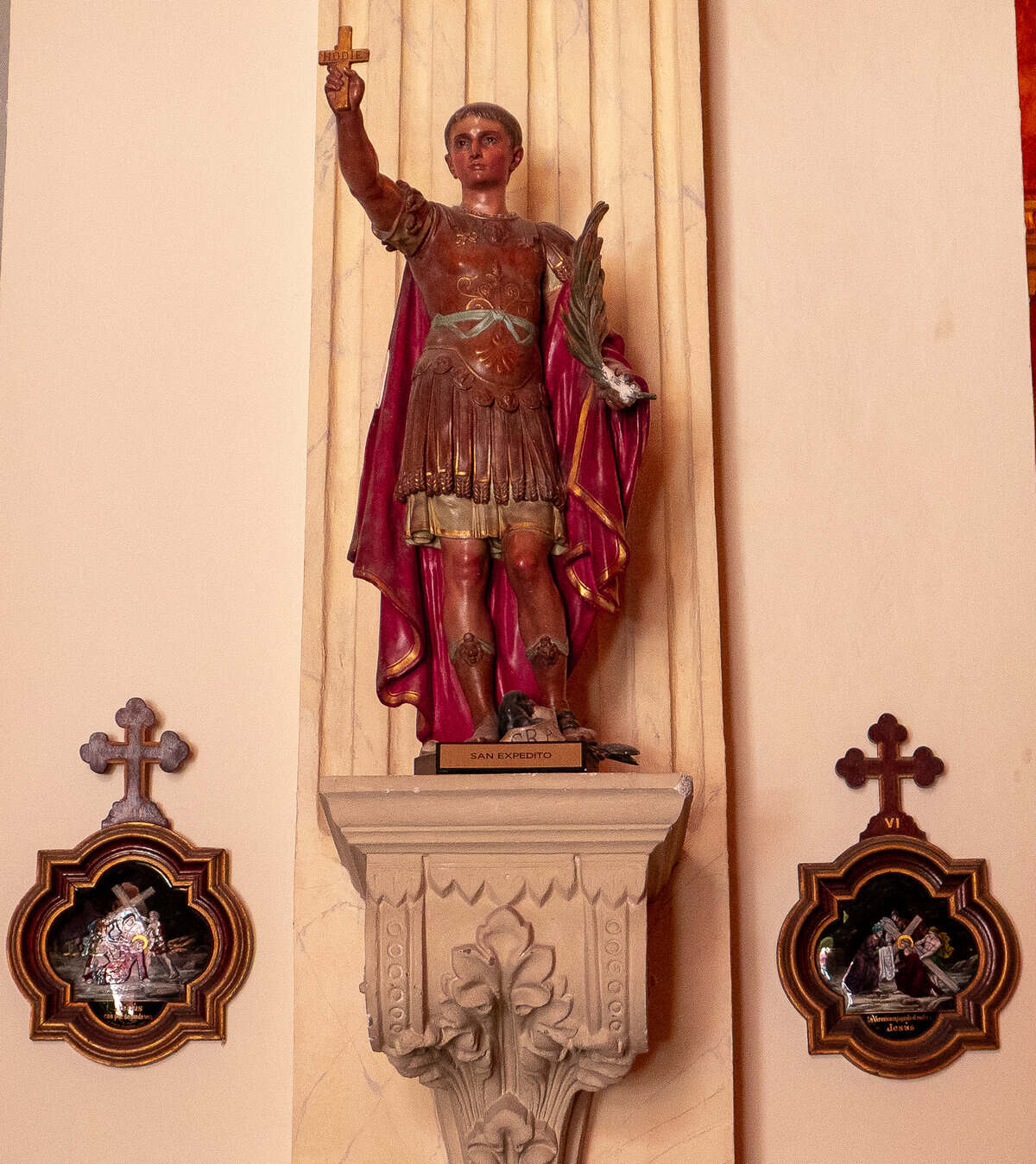 Statue of Saint Expeditus inside the historic Oratorio San Felipe Neri in Casco Viejo, Panama City, surrounded by traditional Stations of the Cross artwork.