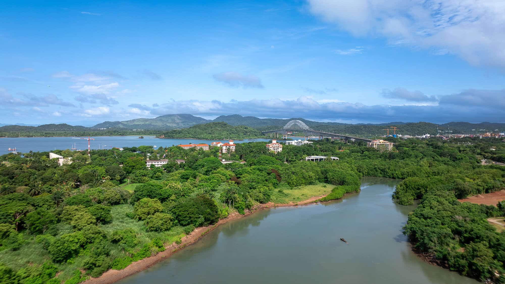 Aerial view of the Bridge of the Americas spanning the Panama Canal above the lush rainforest and waterways near Panama City, Panama.