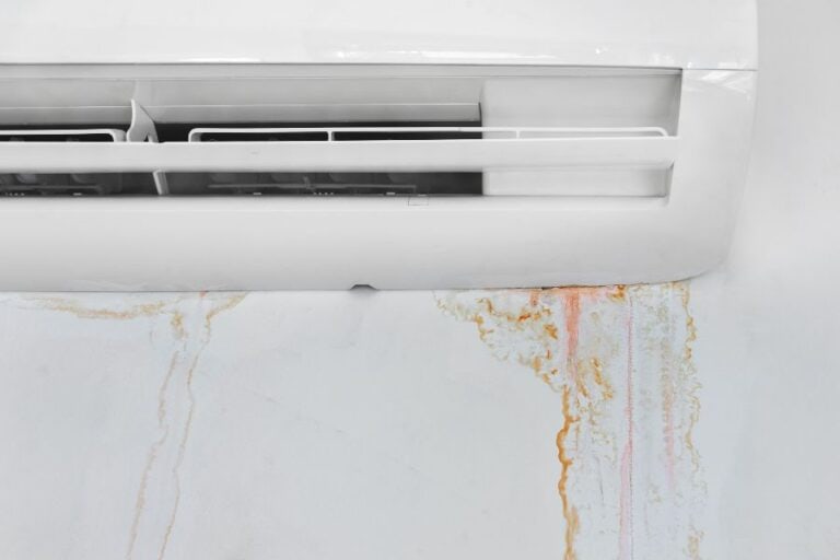 Close-up of air conditioner unit with visible water leak, showing common AC problem.