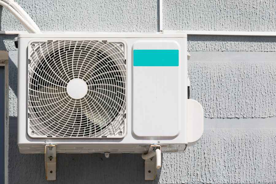 Outdoor reverse cycle air conditioner unit mounted on a building wall for heating and cooling use.