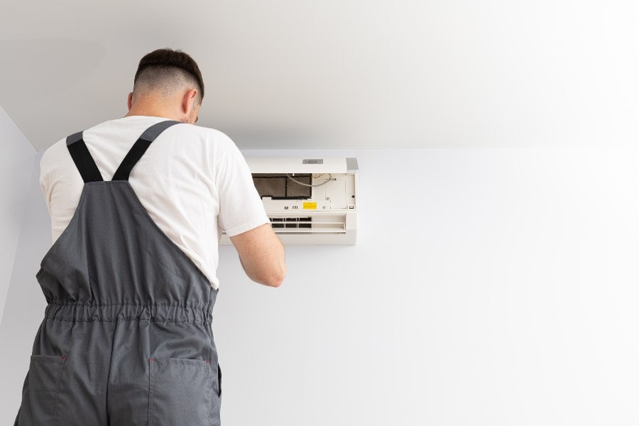 Technician servicing a wall-mounted air conditioner for year-round comfort and efficiency.