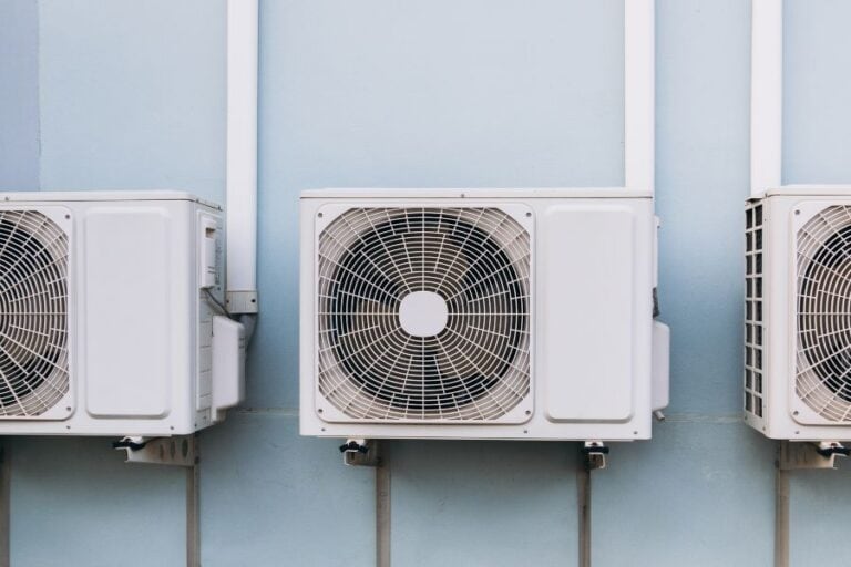 Row of three outdoor air conditioning units mounted on a wall, illustrating modern cooling technology.