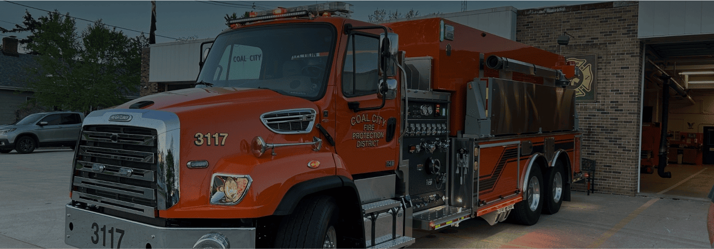 Red fire truck parked outside fire station at dusk