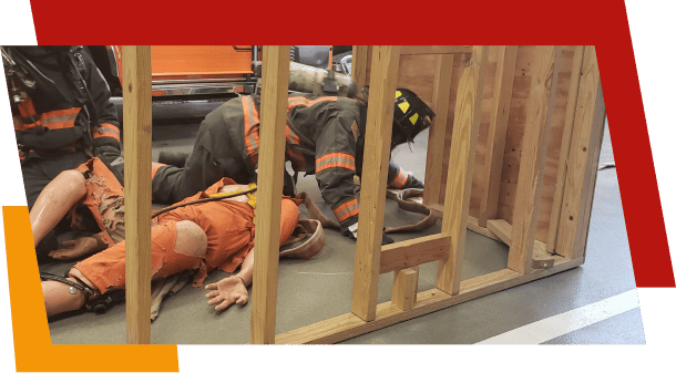 Firefighters training in rescue simulation with orange dummy