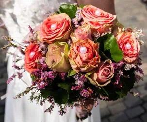 Bunter Hochzeitsstrauß mit Rosen, Kamille und grünen Blättern, detailreiche Nahaufnahme.