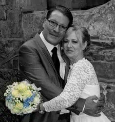 verliebtes Brautpaar in sepia mit gelbem Blumenstrauss