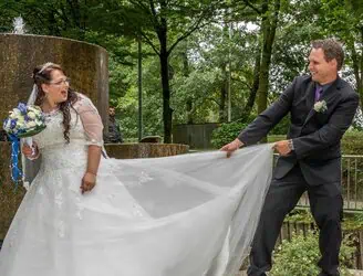 Lachendes Brautpaar bei der Hochzeitsfotografie im Grünen.