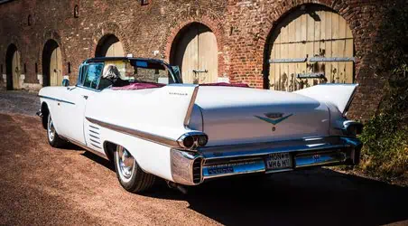 Elegantes weißes Cadillac Auto vor historischem Backstein-Garagentor in Aachen.