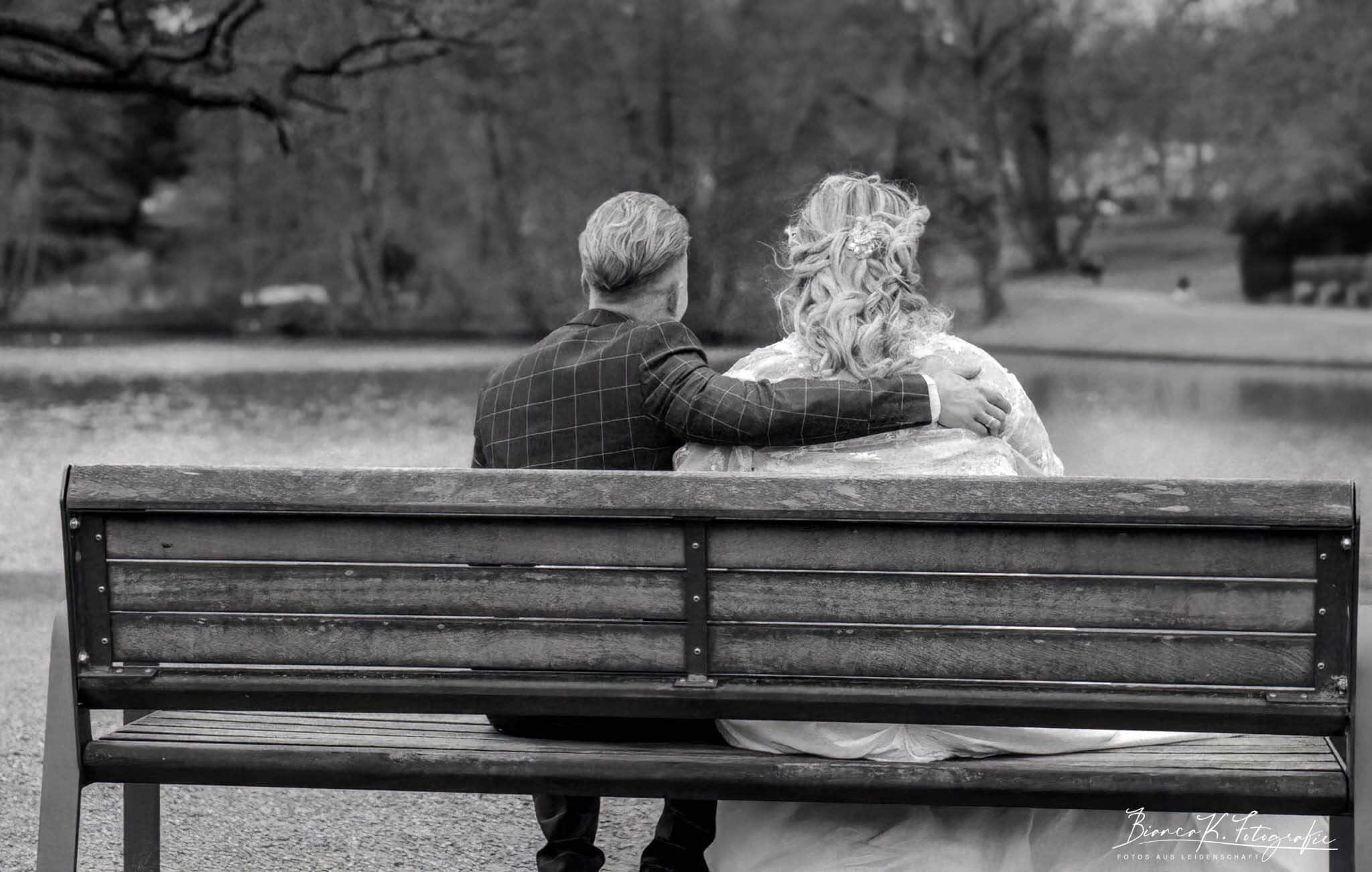 Romantisches Brautpaar auf Parkbank mit Blick auf den See, Schwarz-Weiß-Fotografie, Hochzeitsfotos, emotionale Traubilder, Hochzeitsfotograf Aachen.