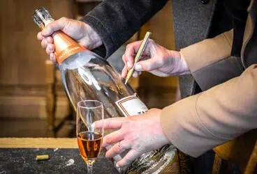 Genießer beim Unterschreiben eines Weinetiketts, intimer Moment bei einer Feier.