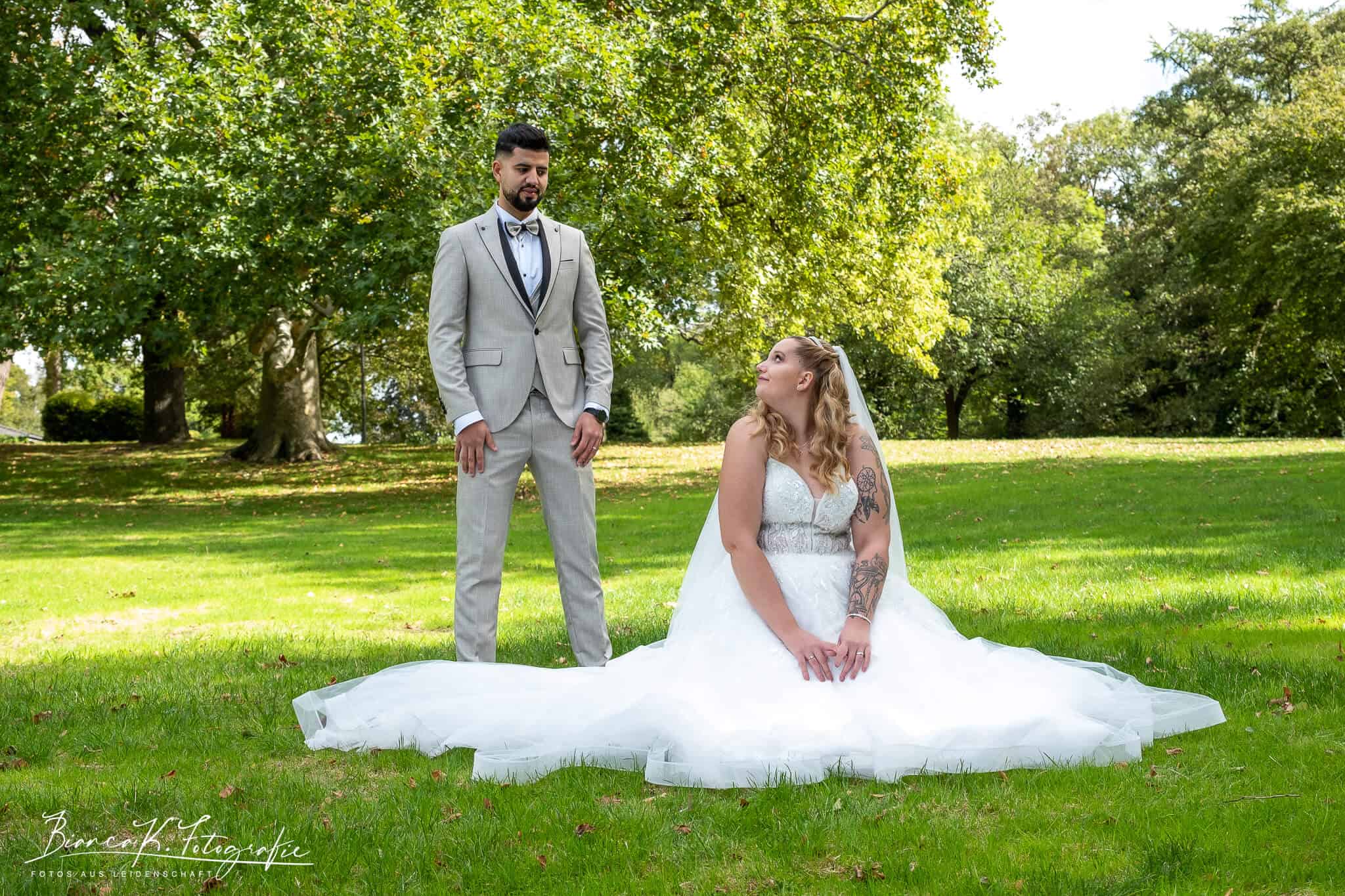 Hochzeit im Grünen, Braut in weißem Kleid und Bräutigam im Anzug bei Outdoor-Fotoshooting.
