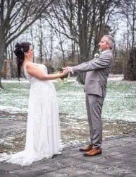 Hochzeitspaar hält sich bei winterlicher Outdoor-Zeremonie die Hände, romantische Atmosphäre, emotionale Momente, Hochzeitsfotograf Aachen.