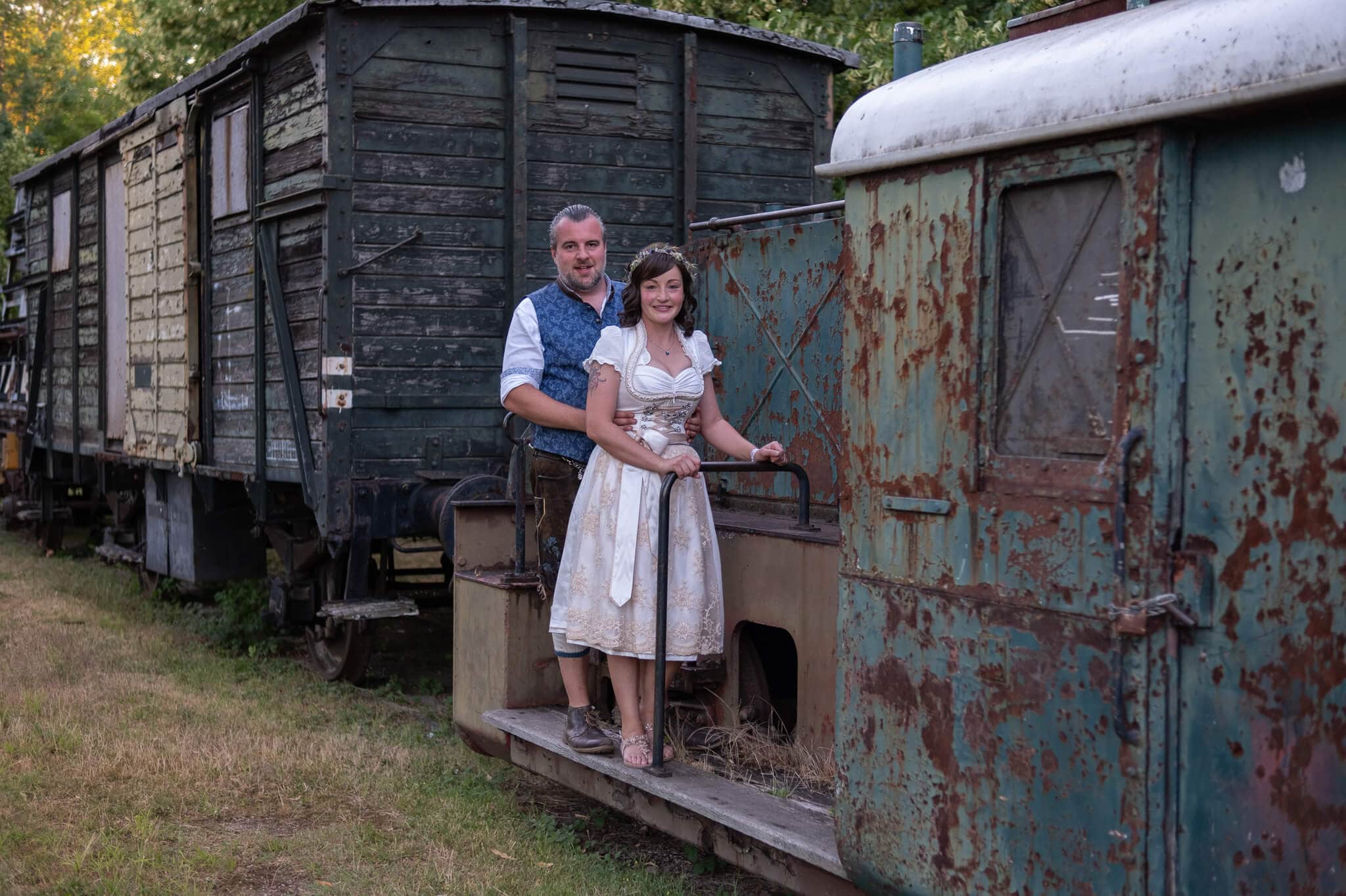 Verlobtes Paar in Traukleidung auf einem alten Eisenbahnwagen, Vintage Hochzeitsfotografie in Aachen.
