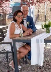 Hochzeitspaar bei outdoor Zeremonie mit Blumen und eleganten Kleidern.