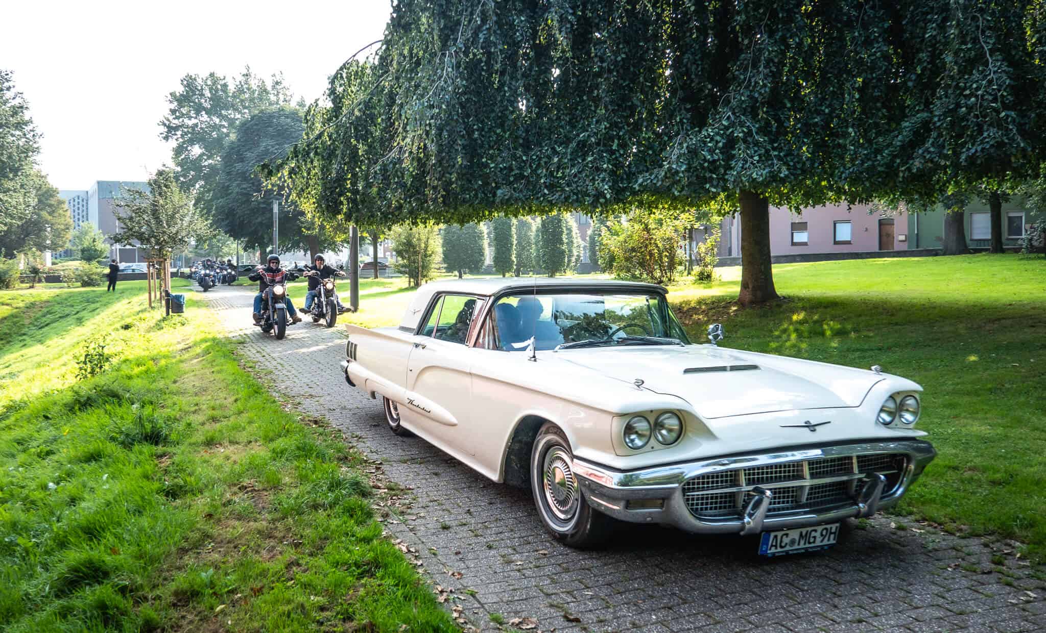 Alte weiße Auto und Motorradfahrer in einem Park in Aachen, schön fotografiert.