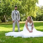 Hochzeit im Grünen, Braut in weißem Kleid und Bräutigam im Anzug bei Outdoor-Fotoshooting.