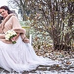 Hochzeitsfoto im Winter, Braut und Bräutigam sitzen auf einer Parkbank, unter Bäumen mit frostigem Hintergrund, bei einer Hochzeit in Aachen.