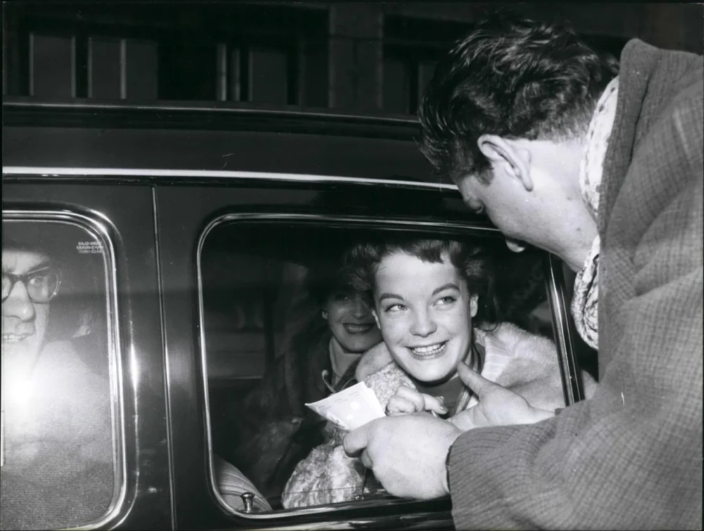Romy Schneider lehnt sich aus einem Wagen und nimmt einen Zettel entgegen, umlagert bei einem Besuch in Hannover