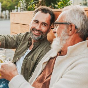 Gute gelaunter Erwachsener Sohn und Vater stoßen mit einem Bier an