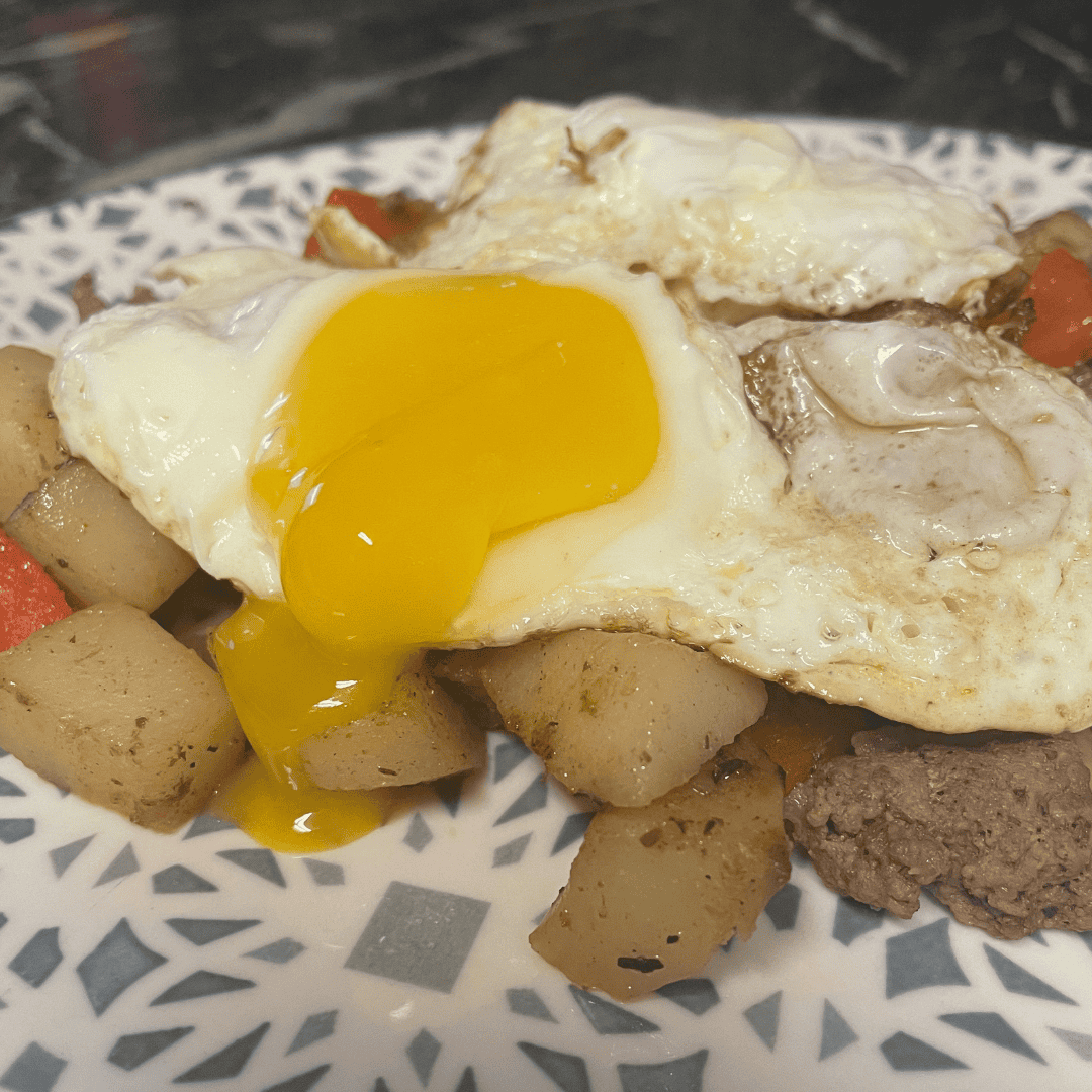 broken fried egg over hamburger hash