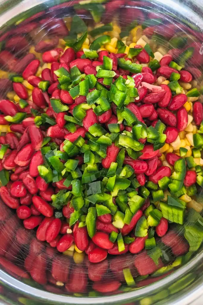 adding chopped jalapeno peppers to corn salad