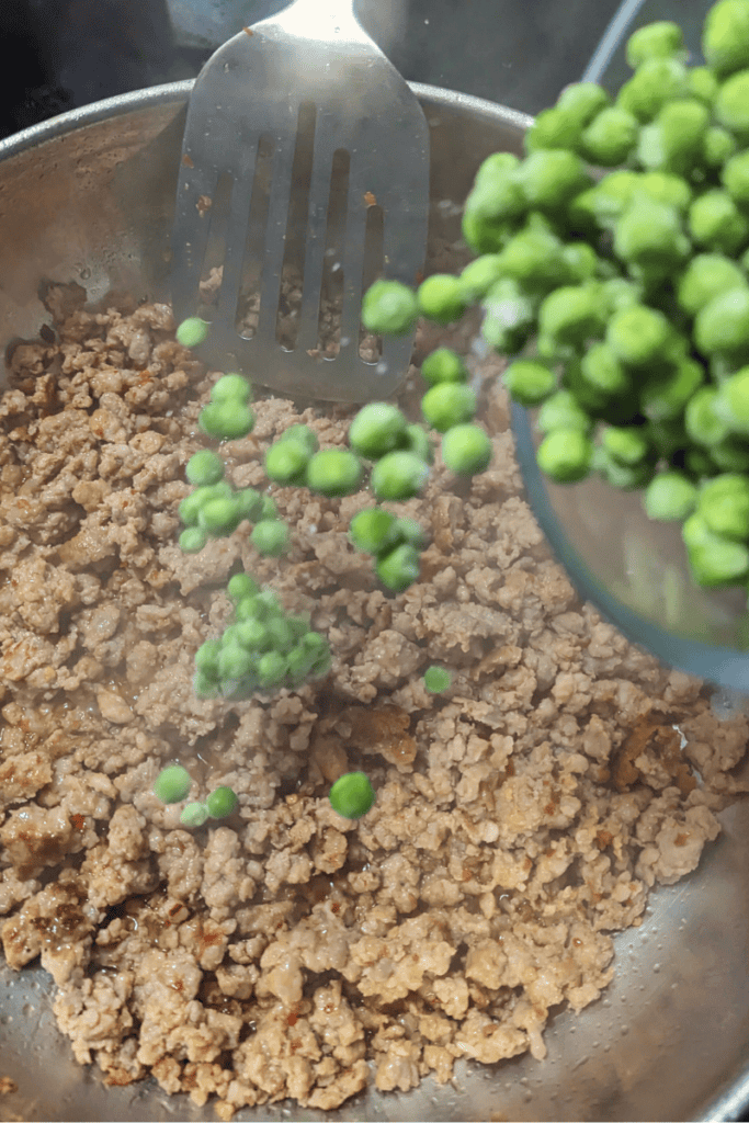 adding frozen peas to browned sausage meat