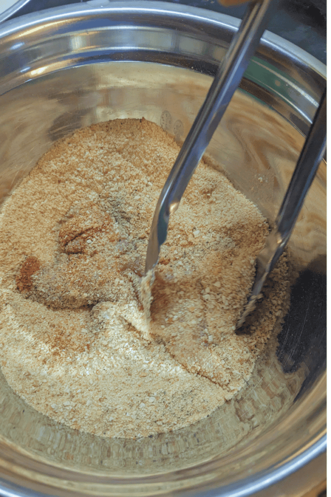 using tongs to roll chicken around in bread crumb mixture for pan-fried chicken tenders